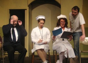 Dr. Spivey (Jim Douglas) and Nurse Flynn (Sonia Richards) look on as Nurse Ratched (Carol Allard Vancil)  examines the case files of McMurphy (Sean Gardell).